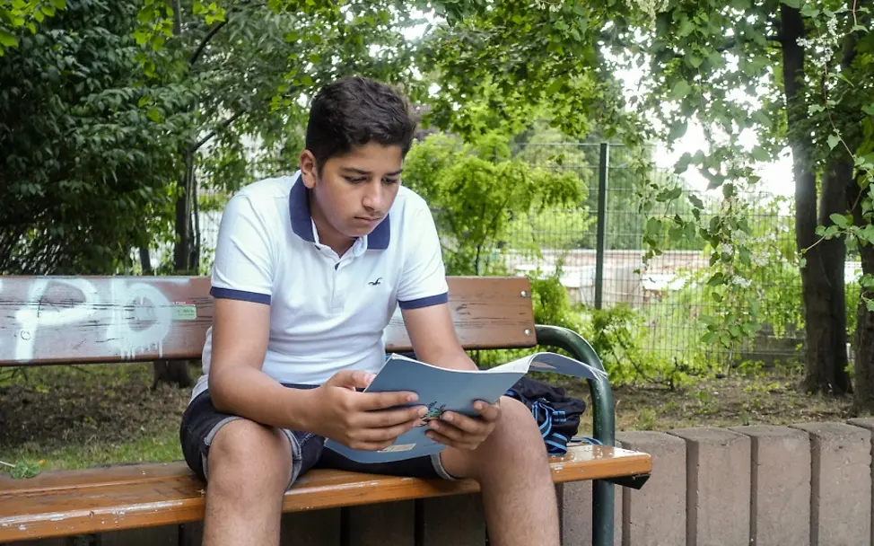 UNICEF-Report Kindeswohl in reichen Ländern: Junge auf Parkbank mit Schulheft