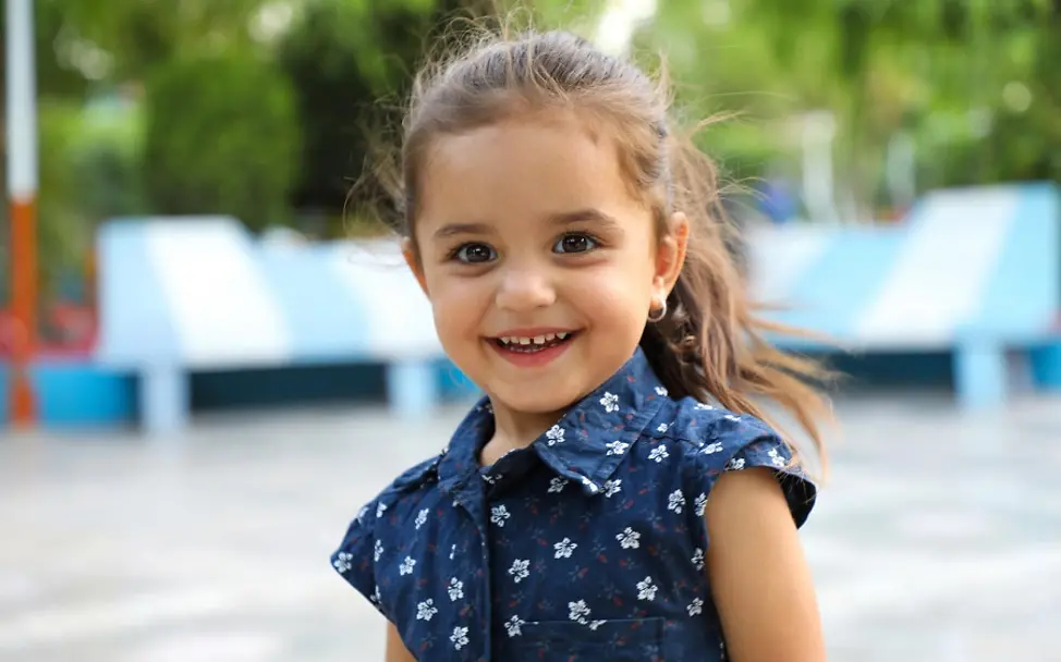 Rahila aus Afghanistan freut sich, dass sie wieder im Park spielen kann. | © UNICEF/Fazel Kindersterblichkeit und Covid-19: Mädchen aus Afghanistan lacht in die Kamera.