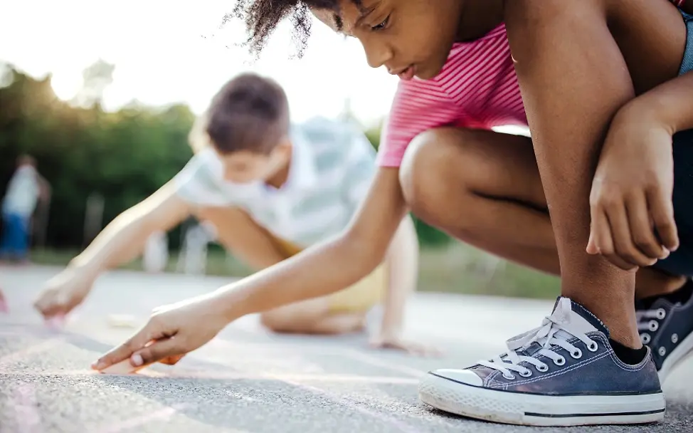 Weltkindertag: Kinderrechte schaffen Zukunft | © iStock.com/Pekic Weltkindertag: Ein Junge und ein Mädchen malen mit Kreide auf die Straße