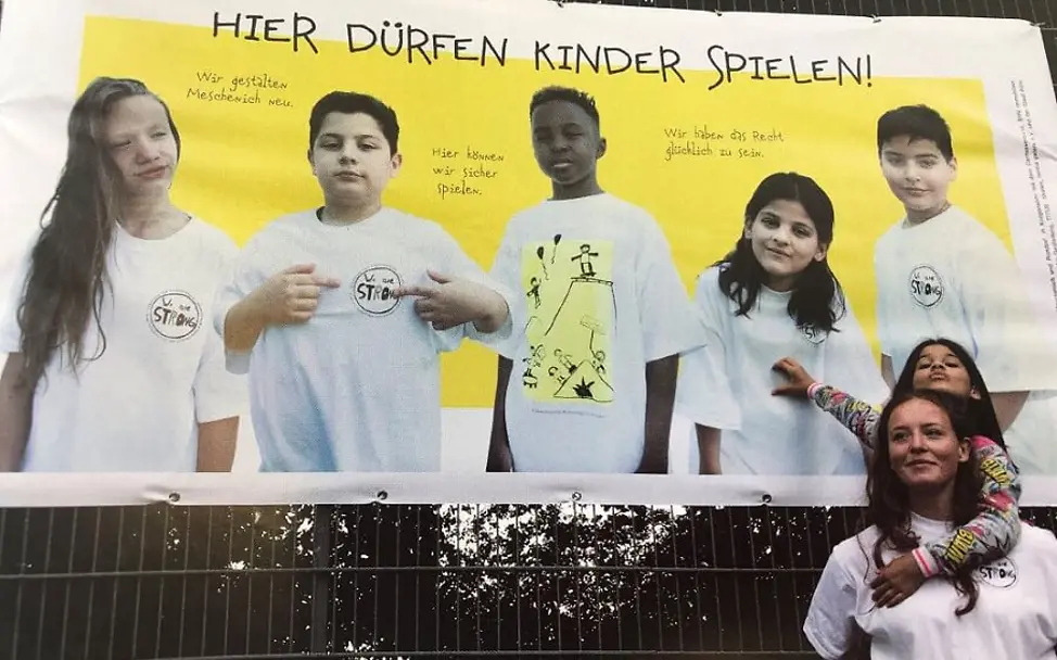Kölnberg: Mutter und Tochter vor einem Plakat des neuen Skateparks.