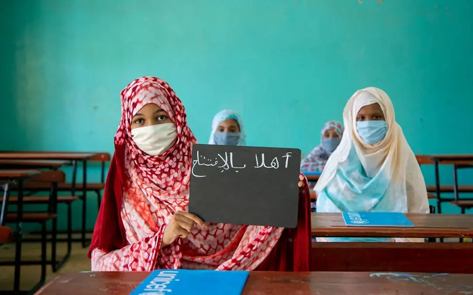 Covid-19: Zwei Mädchen aus Mauretanien mit Schild "Ich liebe Schule" auf Arabisch