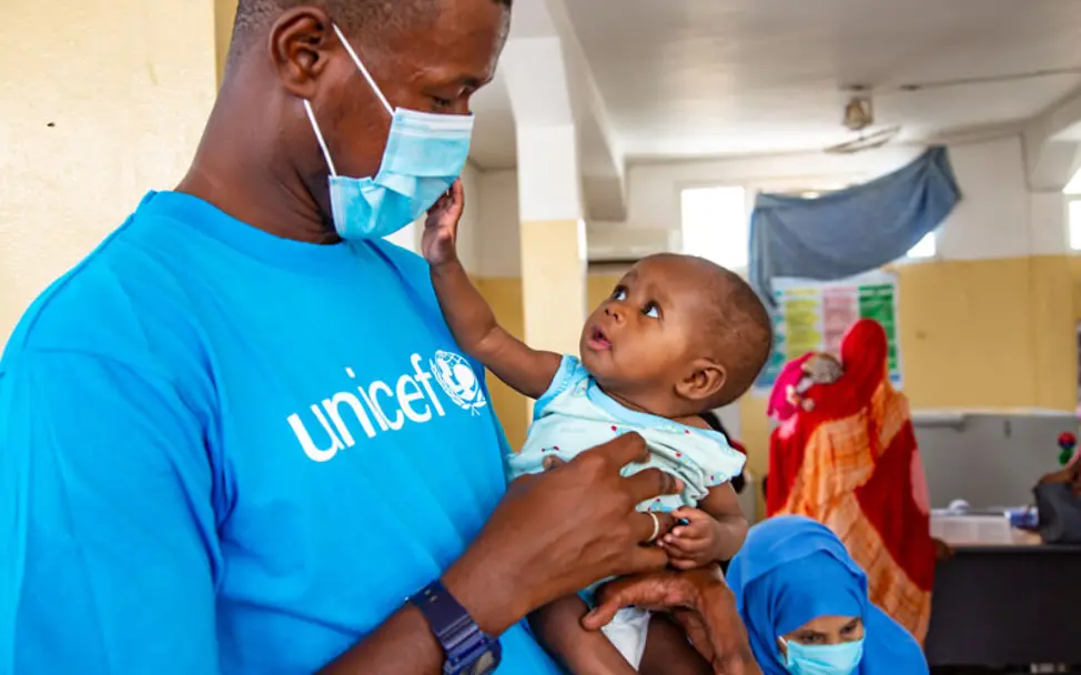 Mauretanien: Corona und Mangelernährung: Ein Baby fasst einem Helfer an die Maske | © UNICEF/Pouget Mauretanien: Corona und Mangelernährung: Ein Baby fasst einem Helfer an die Maske