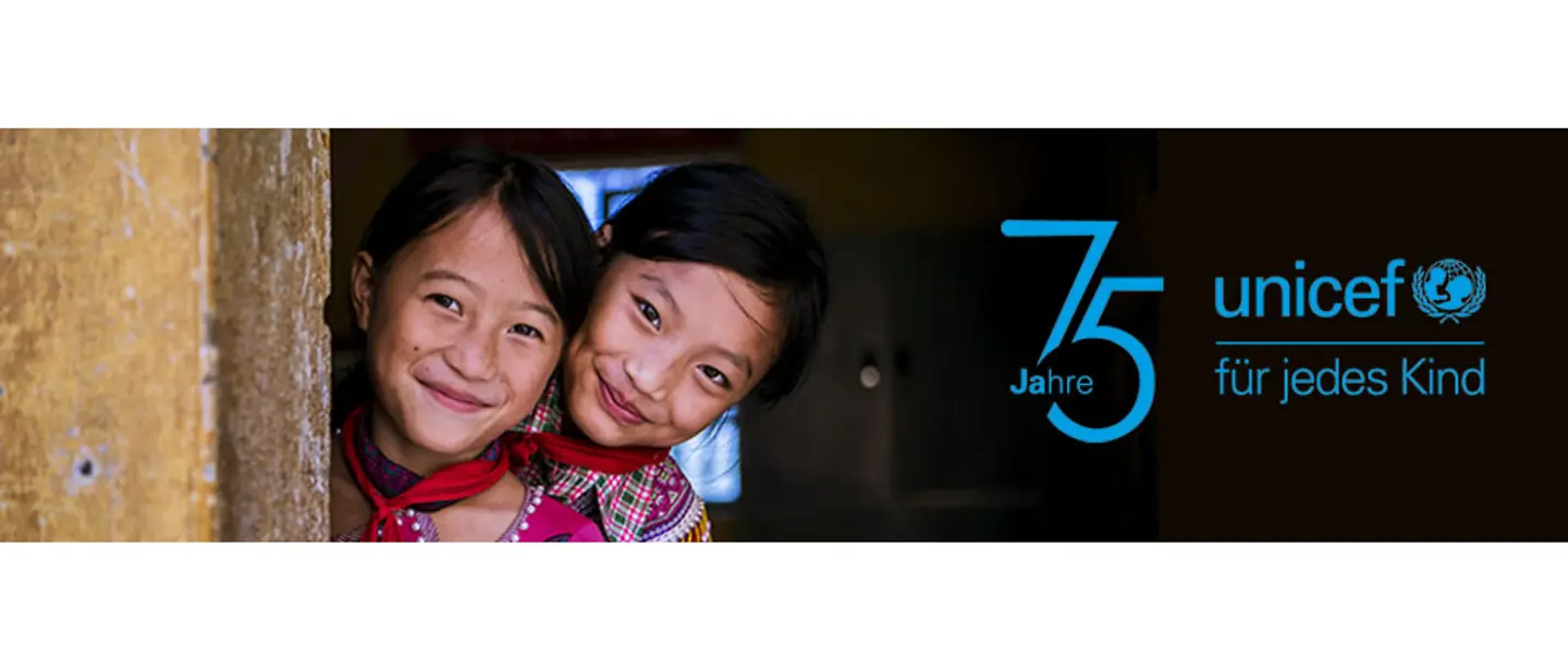 UNICEF wird 75 Jahre alt! 1946 wurde das Kinderhilfswerk der Vereinten Nationen gegründet. | © UNICEF Zwei Mädchen gucken lächelnd hinter einer Mauer hervor.
