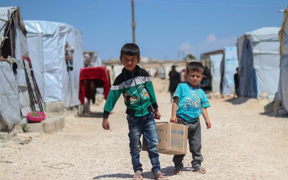 Syrien 2020: UNICEF-Hilfe für Flüchtlingskinder | © UNICEF/UNI334456/Almatar Syrien 2020: Zwei Brüder tragen ein UNICEF-Hilfspakets mit Hygiene-Produkten zum Schutz vor Covid-19