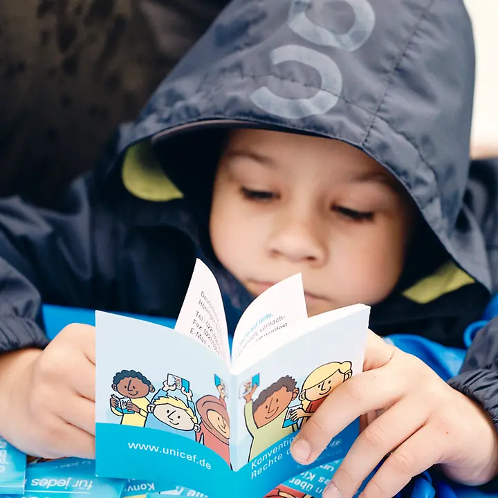 Ein Kind blättert im Kinderrechte-Booklet