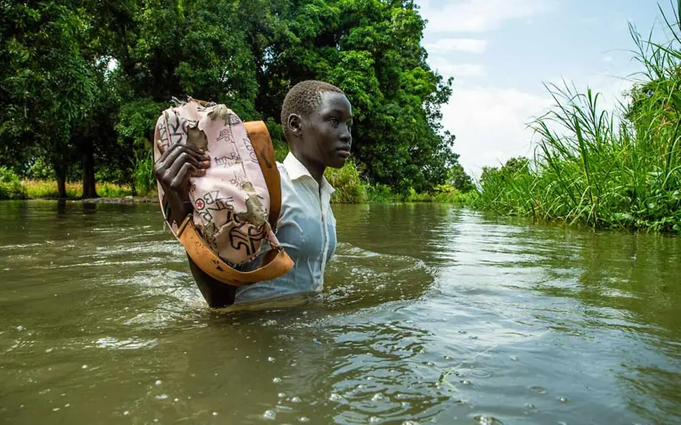 Naturkatastrophen spenden: Durch den Klimawandel kommt es immer häufiger zu Überflutungen. | © UNICEF/CHOL Naturkatastrophen - spenden für Nothilfe: Ein Mädchen im Südsudan watet durch das Hochwasser.