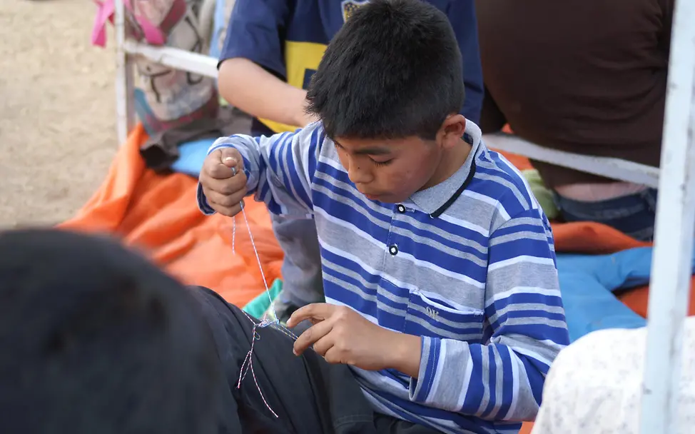 Argentinien: Ein Junge knüpft beim Kinderfest ein Armband. | UNICEF Blog