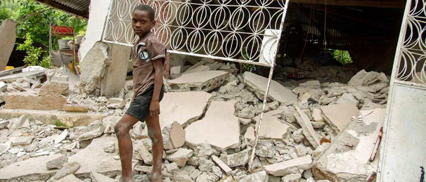 Haiti: Ein Junge steht nach einem Erdbeben auf den Trümmern eines Wohnhauses. | © UNICEF/Rouzier Haiti spenden: Wir leisten Nothilfe nach Katastrophen und unterstützen Haitis betroffene Familien beim Wiederaufbau.