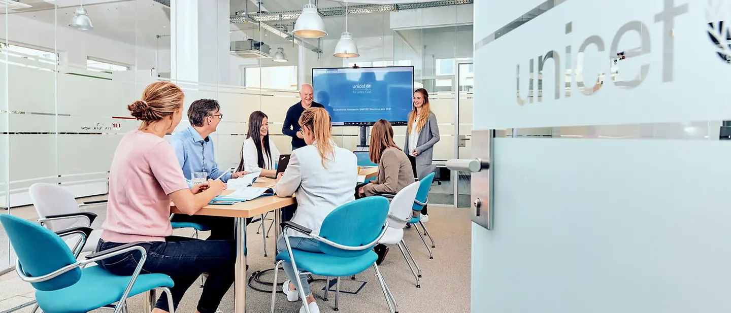 Karriere bei UNICEF | © UNICEF/UN0521129/Bänsch Mitarbeitende von UNICEF Deutschland sitzen bei einem Meeting in einem Konferenzraum des kölner Büros.