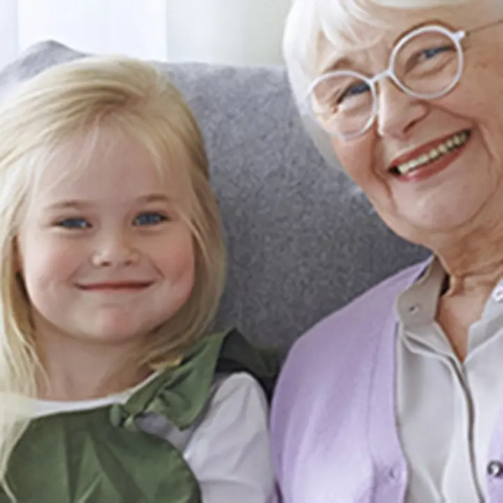 Ein Mädchen sitzt mit einer älteren Dame auf einem Sofa