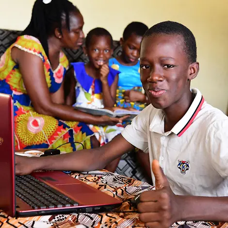 Mit dem Laptop lernt es sich von überall. | © UNICEF/Frank Dejongh Elfenbeinküste: Alain (12) lernt von im Wohnzimmer.
