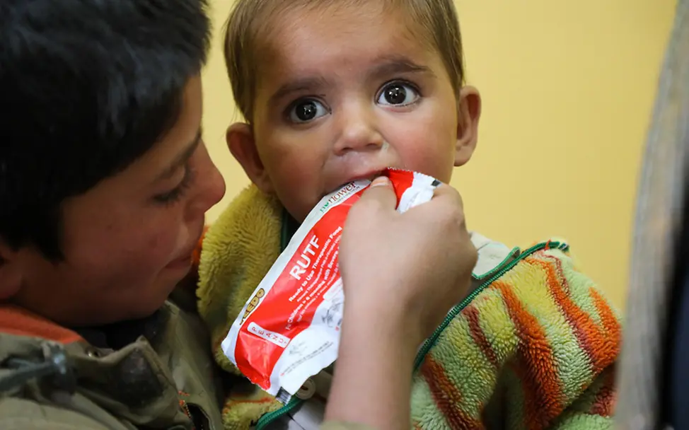 Afghanistan: Ein Junge füttert seinen kleinen Bruder mit Erdnusspaste