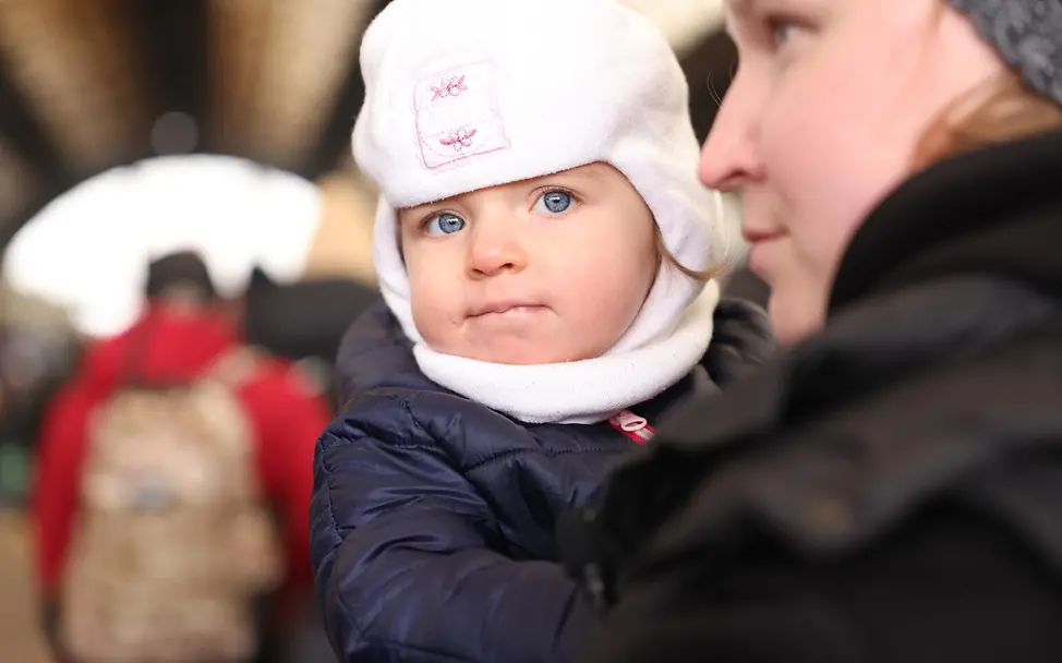 Am 27. Februar wartet Asya mit einem Kleinkind auf einem Bahnhof im Westen der Ukraine auf einen Evakuierungszug. | © UNICEF/Moskaliuk Vom Bürgerkrieg zum Krieg in der Ukraine: Am 27.2. wartet Asya mit einem Kleinkind auf dem Bahnhof im Westen der Ukraine.
