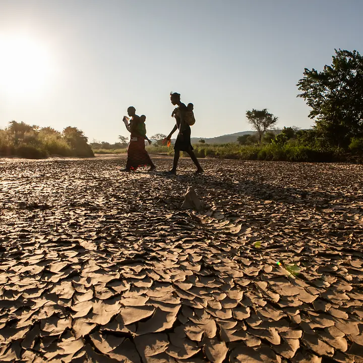 Menschen laufen auf vertrocknetem Boden in Sambia © UNICEF/Schermbrucker UNI308044