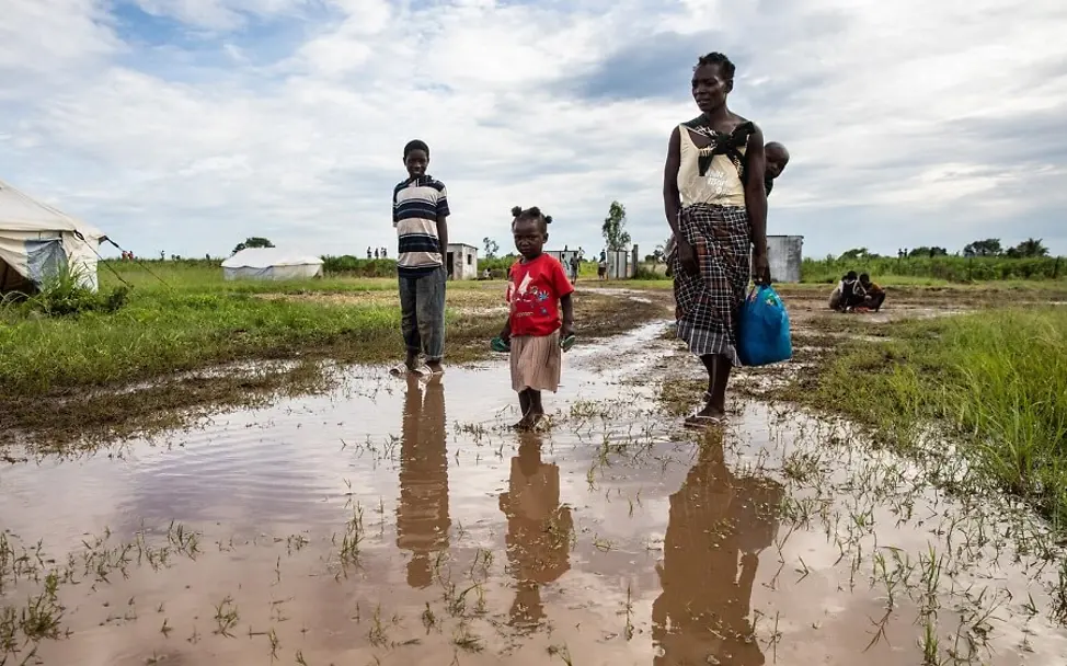 Eine Mutter läuft mit ihrem Kind über ein überschwemmtes Feld. 