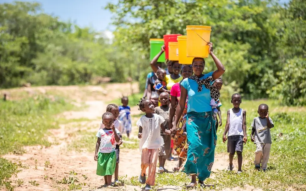 Frauen tragen bunte Eimer auf ihren Köpfen.