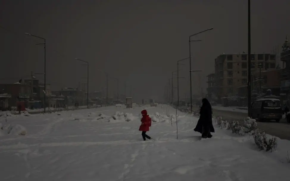 Eine Mutter läuft mit ihrer Tochter durch die verschneiten Straßen von Kabul.