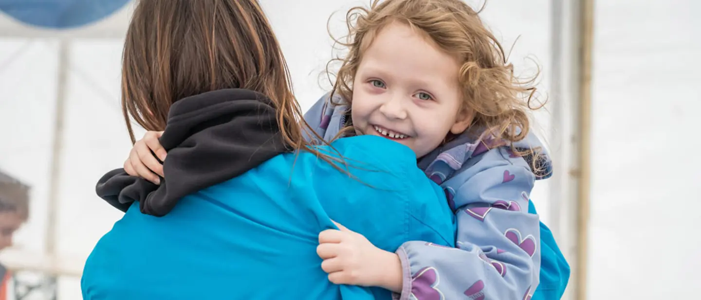 Ukraine-Krieg: Eine Helferin spielt mit einem Kind in einer Anlaufstelle für Geflüchtete | © UNICEF/Holerga Eine UNICEF Helferin trägt ein lachendes Kind auf dem Arm in einer Anlaufstelle für Geflüchtete