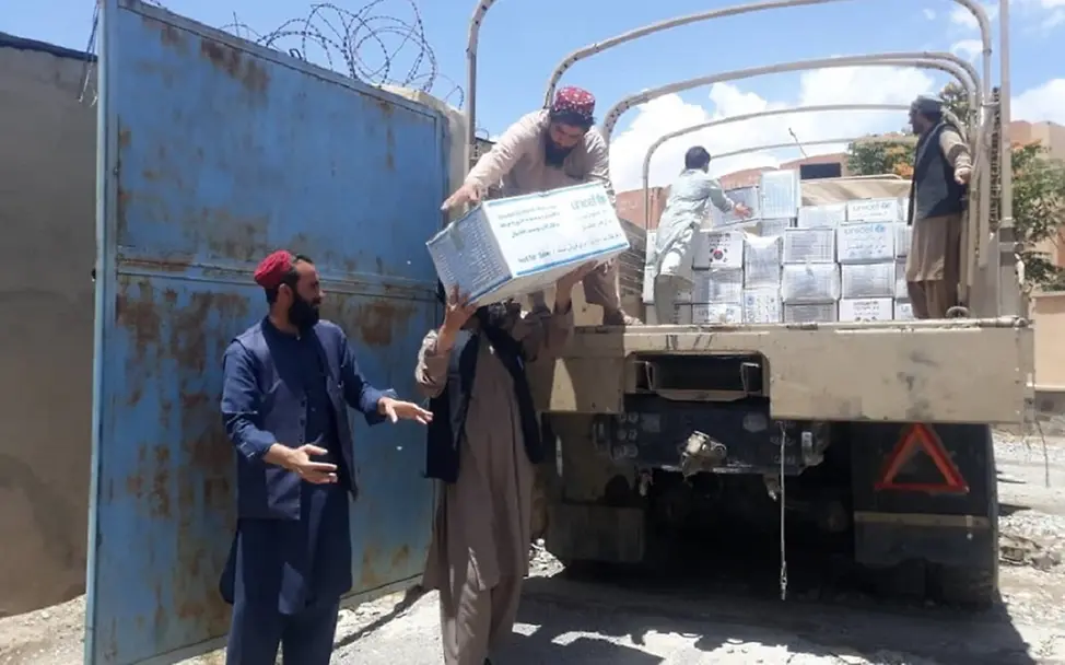 Männer heben Hilfsgüter aus einem Wagen.