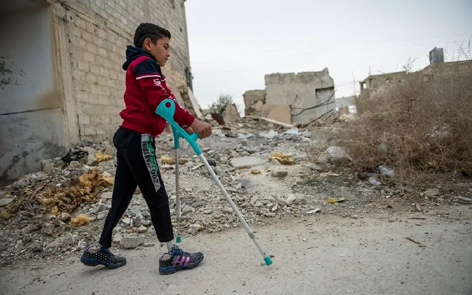 Syrien: Eine Junge läuft auf Krücken einen Weg entlang.