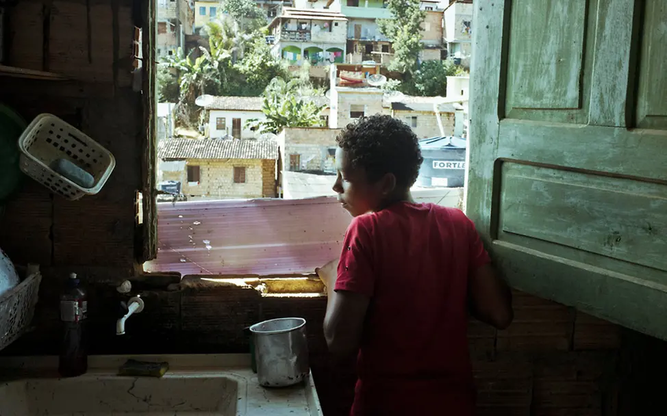 Caio steht am Fenster und blickt auf die Stadt. | © UNICEF/De Middel/Magnum Photos Brasilien: Caio steht am Fenster und schaut nach draußen.