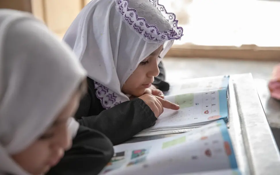 Mädchen in Afghanistan | © UNICEF/Bidel Afghanistan: Zwei Mädchen schauen auf ein Lernbuch.