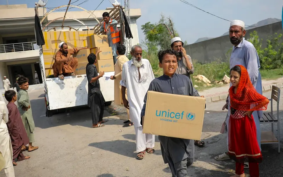 Pakistan: Überschwemmungen | © UNICEF/UN0696514/Zaidi Pakistan: Junge trägt UNICEF-Hilfspaket davon.