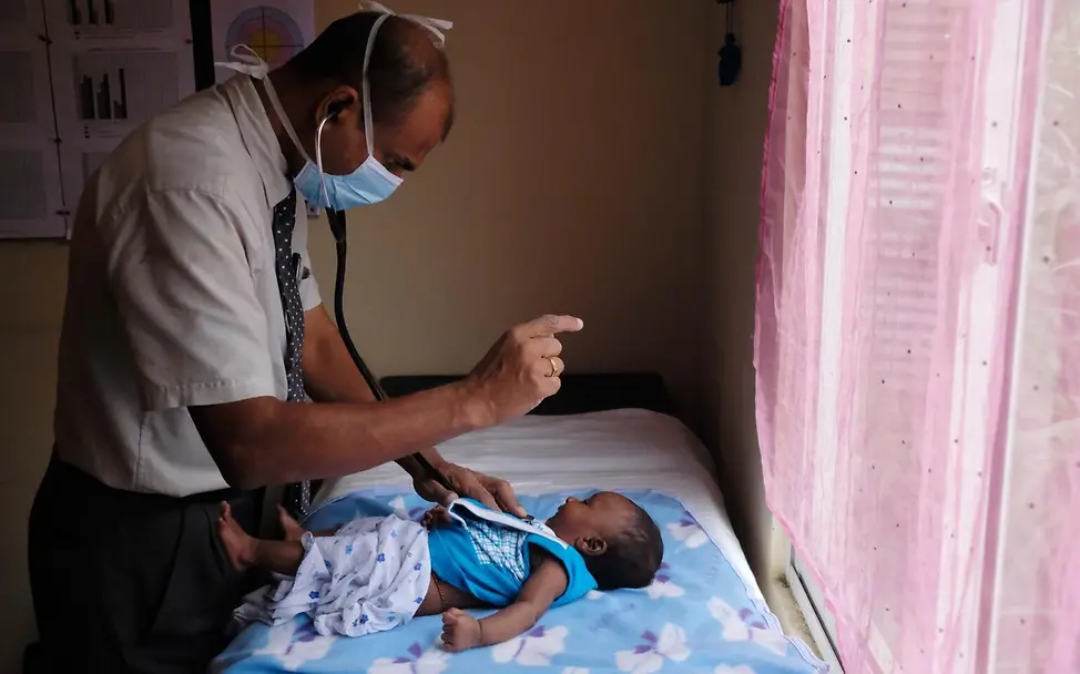 Dr. Ruwan Jayasingha untersucht ein Kleinkind. | © UNICEF/UN0649776 Ein Arzt untersucht ein Kleinkind auf einer Gesundheitsstation.