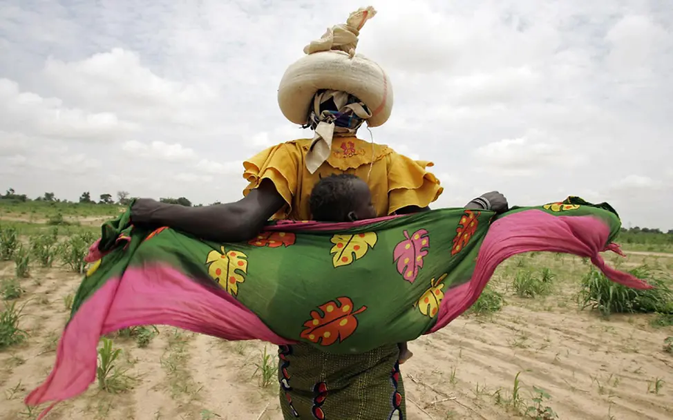 Saiibou, Mutter der 2-jährigen Harea trägt Hirse auf ihrem Kopf. | © UNICEF/Chalasani Saiibou, Mutter der 2-jährigen Harea trägt Hirse auf ihrem Kopf.