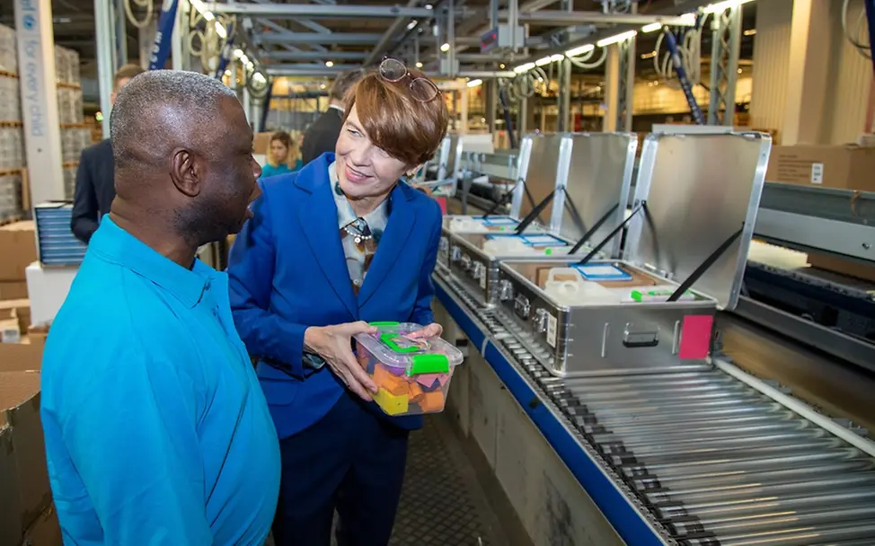 Elke Büdenbender im UNICEF-Logistikzentrum I Mikkelsen/UNICEF Elke Büdenbender hält ein Paket mit Schulmaterial in den Händen.