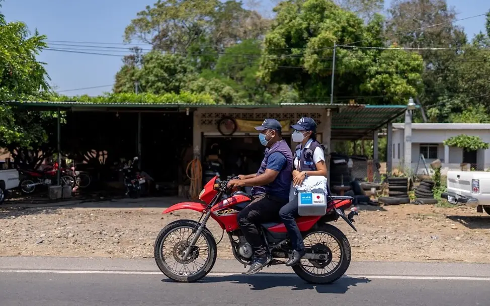 In Guatemala erreichen Impfungen die Kinder per Motorrad. | © UNICEF/Billy/AFP-Services Guatemala: Eine Krankenschwester wird auf einem Motorrad gefahren.