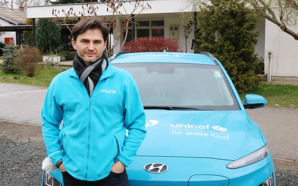 Lenn Kudrjawizki am Auto | © UNICEF/Ilej Lenn Kudrjawizki vor Auto mit UNICEF-Beschriftung