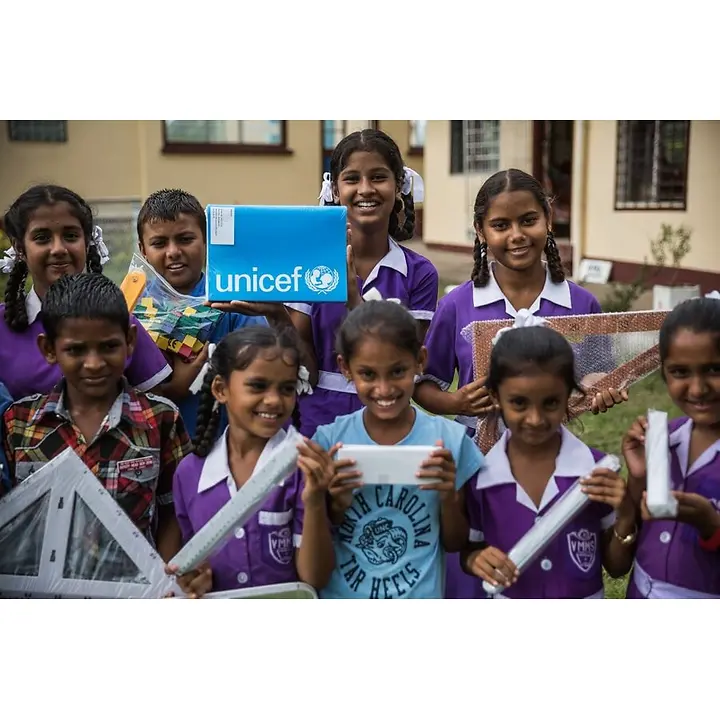 Schule in der Kiste Kinder halten die Hilfsgüter fröhlich hoch