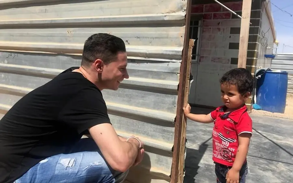 Julian Draxler trifft Abdullah von Familie Jundi aus dem letzten Jahr wieder. | © UNICEF/Berger Jordanien: Julian Draxler hockt vor dem kleinen Abdullah