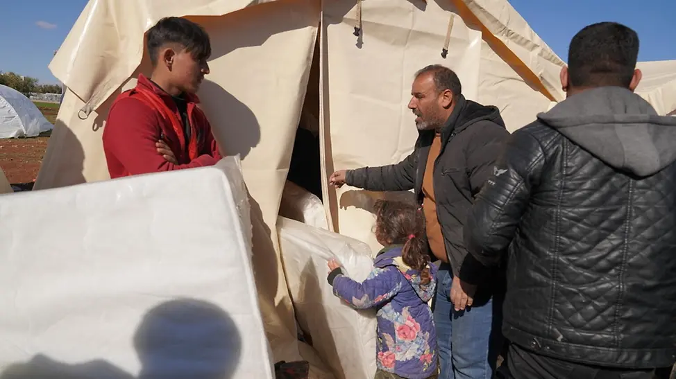 Erdbeben in Syrien: Familien tragen Hilfsgüter wie Matratzen in ihr behelfsmäßiges Zelt.