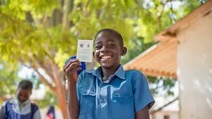 Tichaona aus Zimbabwe zeigt stolz seinen Impfausweis. 