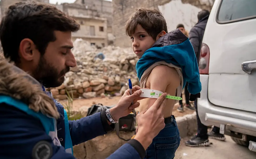© UNICEF/Al-Asadi Syrien: Ein Gesundheitshelfer misst die Breite eines Jungen mithilfe eines Messbandes.