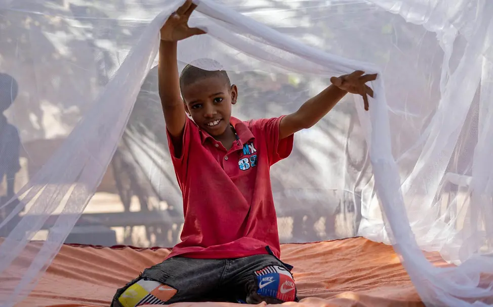 Ein Junge im Sudan unter einem Moskitonetz.