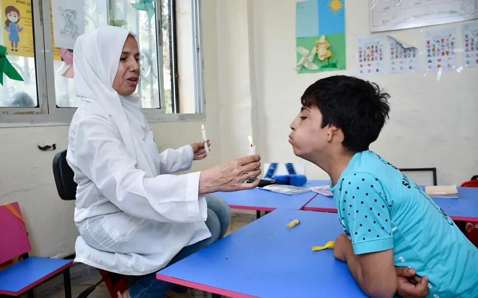 Syrien: Ahmad pustet die Kerze aus, die seine Lehrerin hochhält.
