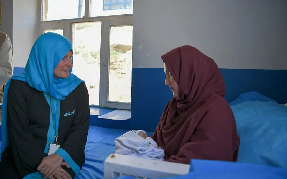 Afghanistan: UNICEF steht weiter an der Seite der Kinder I UNICEF/Karimi Afghanistan: Eine UNICEF-Mitarbeiterin sitzt mit einer Mutter und ihrem Neugeborenen auf einem Bett.