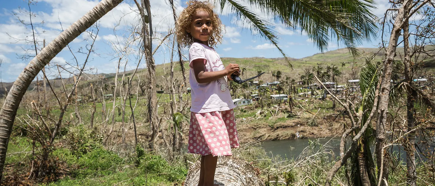 Today & Tomorrow: Kinder vor Klimarisiken schützen | © UNICEF/Sokhin Fidschi: Mädchen steht auf Baum, der durch Zyklon entwurzelt wurde.