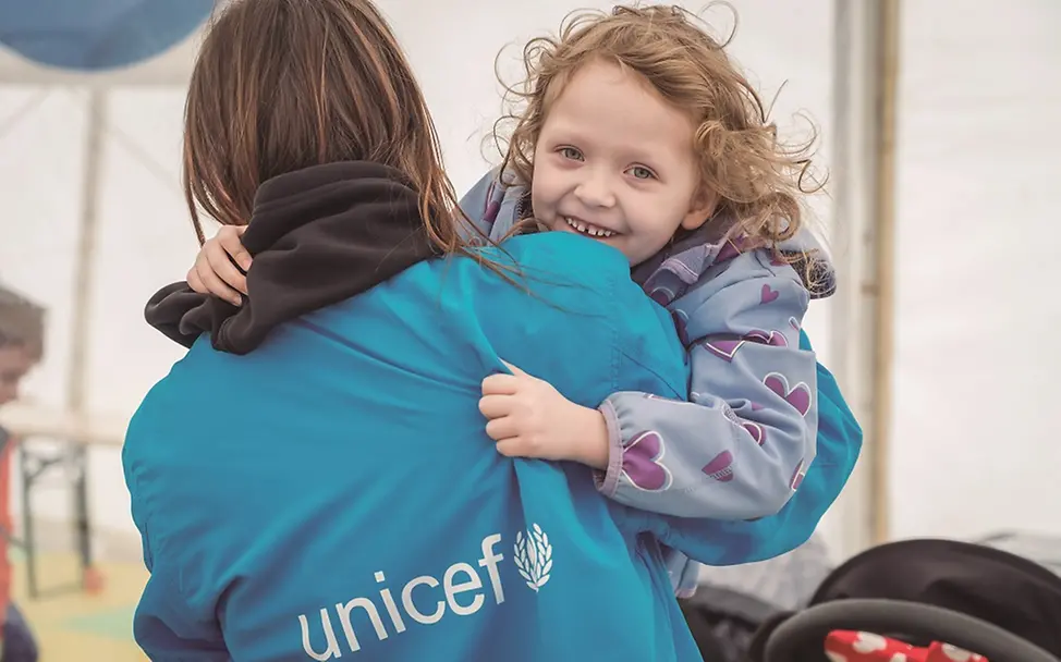 Rumänien: Ein Mädchen auf dem Arm einer Frau schaut lächelnd in die Kamera