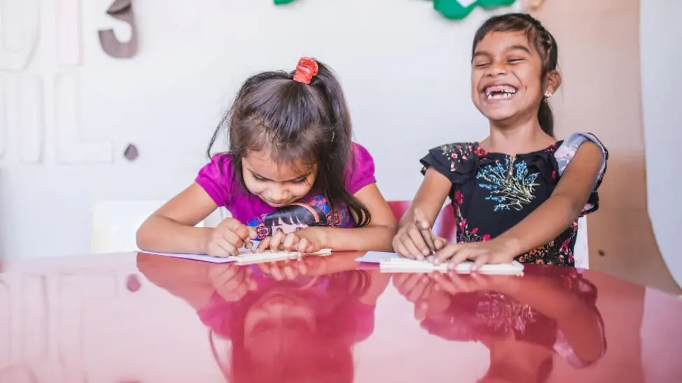 Guatemala: Zwei Schulmädchen sitzen an einem Tisch und lösen Aufgaben.