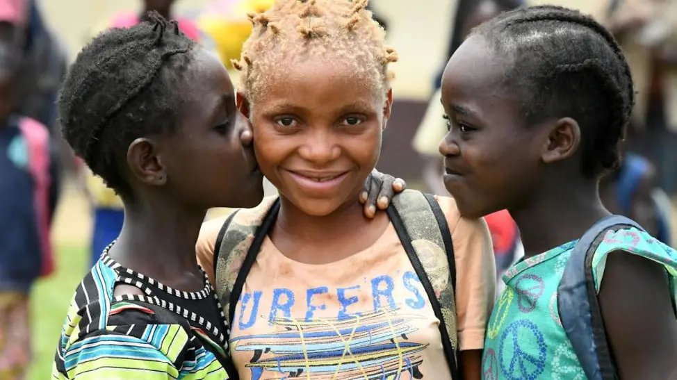 Kongo: Ein Mädchen mit Albinismus steht mit zwei weiteren Mädchen zusammen.