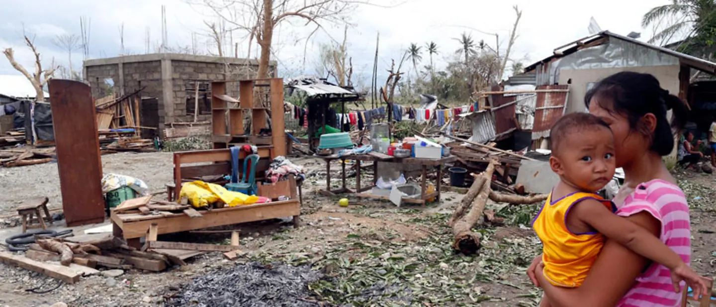 Taifune bringen große Zerstörung mit sich, so wie hier auf den Philippinen | © UNICEF/Maitem Taifun Nothilfe: Eine Mutter auf den Philippinen hält nach einem Taifun ihr Kind auf dem Arm.