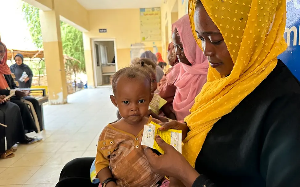 Sudan: Zehntausende Kinder in Lebensgefahr | UNICEF/Awad Sudan: Ein Kind sitzt auf dem Schoß seiner Mutter und wird gefüttert