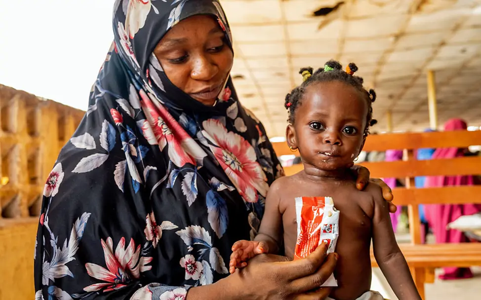 Ein Baby in Nigeria bekommt von seiner Mutter sättigende Erdnusspaste | © UNICEF/Onafuwa Spenden gegen Hunger: Hungernde Kleinkinder wie dieses brauchen dringend Zusatznahrung