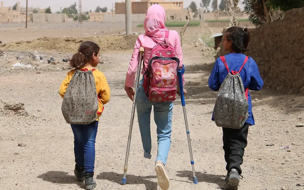 Schwere Kinderrechtsverletzungen in Konflikten I © UNICEF/Al-Kheder Kinder im Krieg: Ein Mädchen in Syrien geht auf Krücken mit Schulkameraden einen Weg entlang