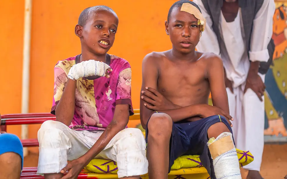 Sudan | © UNICEF/UNI626280/Isamaldeen Zwei Jungen sitzen mit verbundenen Wunden auf einem Krankenhausbett.