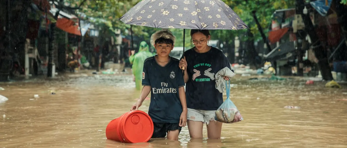 Folgen des Taifun Yagi in Vietnam | © UNICEF/UNI642119/Do Khuong Duy Zwei Mädchen laufe durch knietiefes Wasser in Thai Nguyen, Vietnam, nach dem Taifun Yagi.